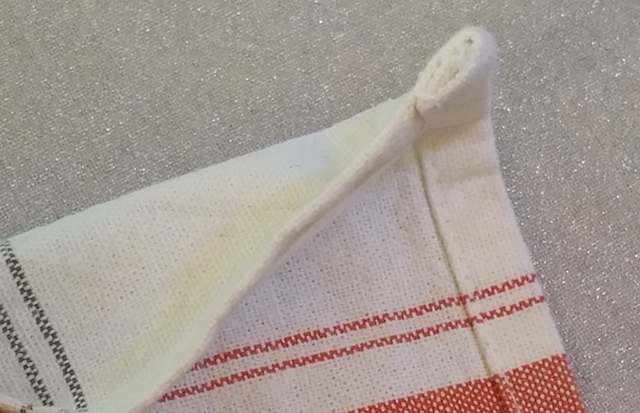 Sur-épaisseurs de tissu dans l'angle d'une serviette de table